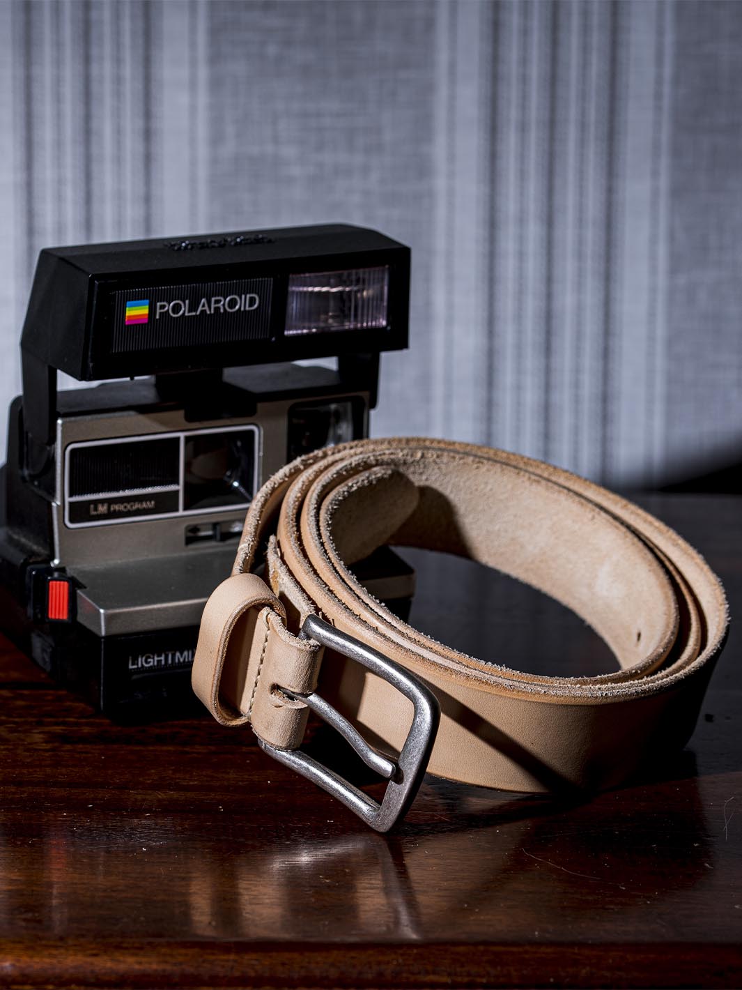 cintura in cuoio da uomo fatta a mano posizionata davanti a una polaroid