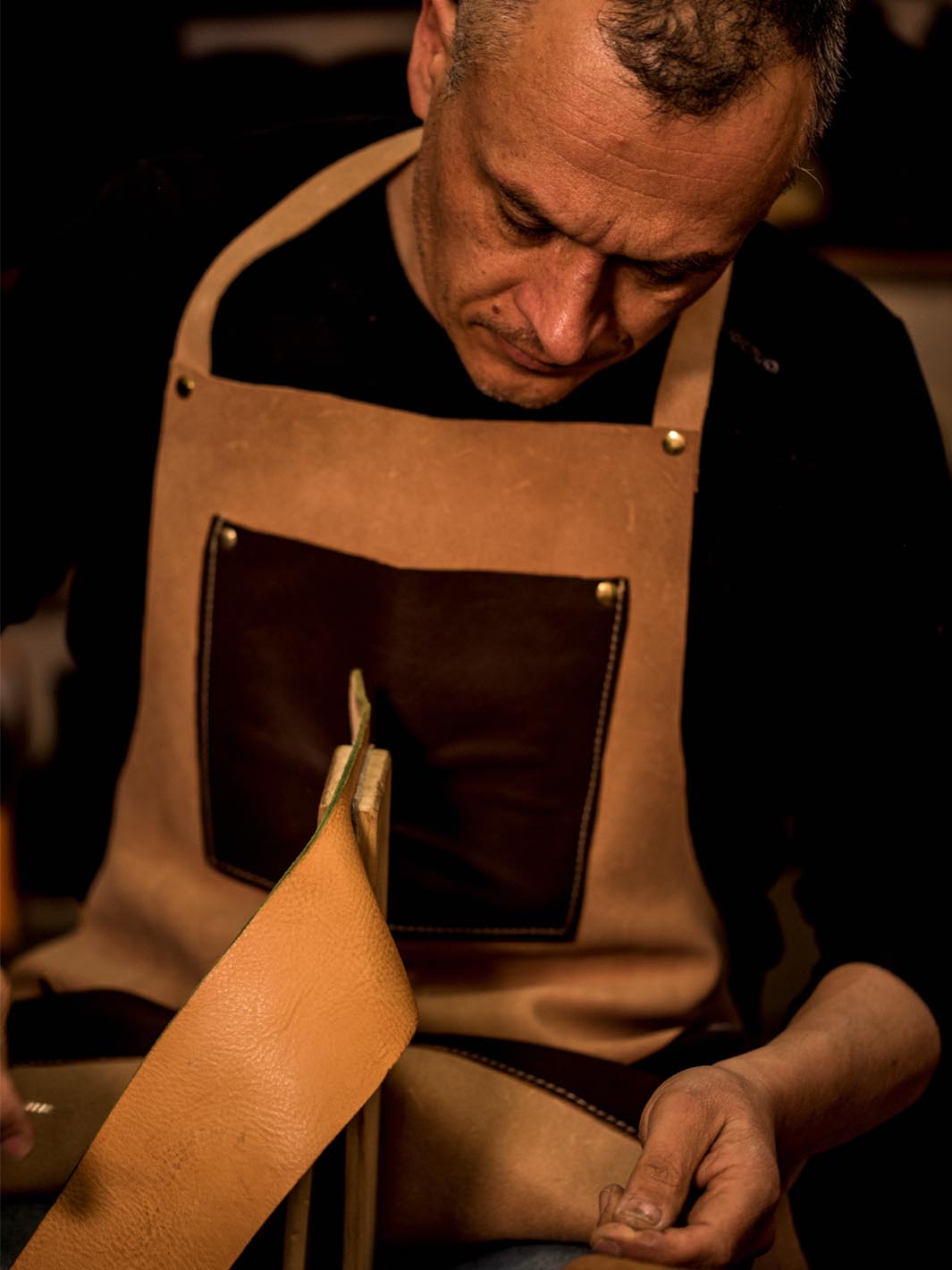artigiano Massimiliano cuce a mano un pezzo di cuoio 