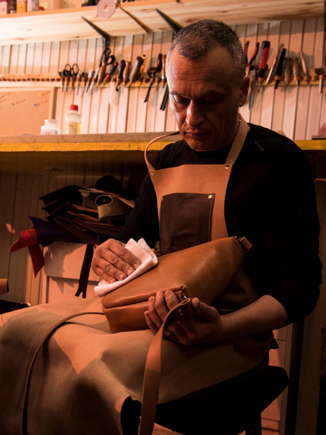 artigiano coryum che lucida una borsa in cuoio nella sua bottega artigianale