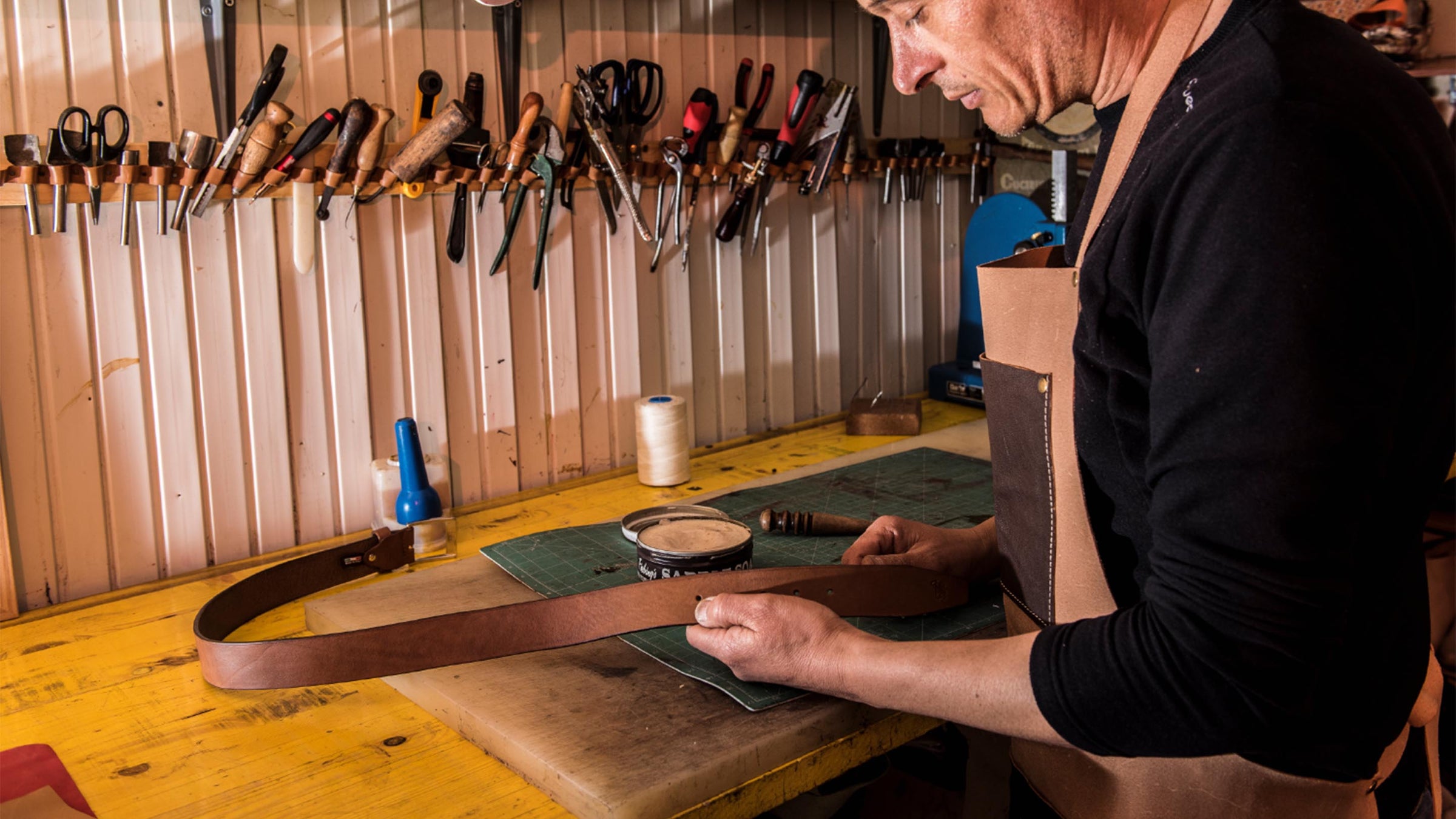 artigiano che lavora a mano una cintura in cuoio da uomo nella sua bottega